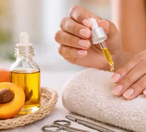 Application d’huile d’abricot sur ongles naturels et cuticules pour un soin nourrissant ciblé.