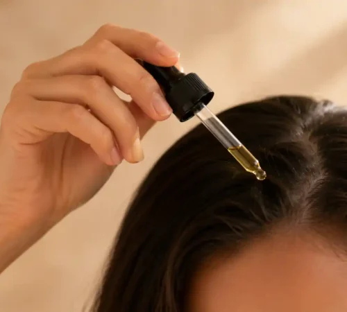 Huile pousse cheveux naturelle : laquelle choisir Application d'une huile naturelle avec un compte-gouttes sur le cuir chevelu pour favoriser la pousse des cheveux